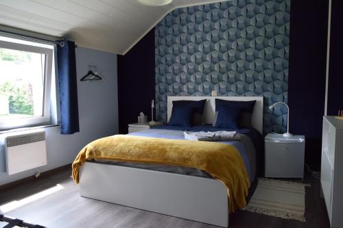 a bedroom with a bed with a blue wall at Chez Martine et Jean-Marc in Tintigny