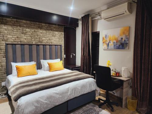 a bedroom with a bed with yellow pillows and a desk at Eastern Road Executive Suites in Harare