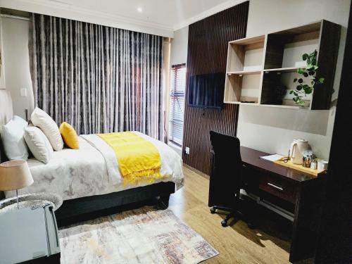 a bedroom with a desk and a bed with a yellow blanket at Eastern Road Executive Suites in Harare