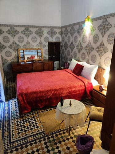 a bedroom with a red bed and a table at Riad Bennouna in Fez