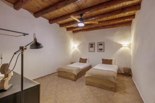 two beds in a room with wooden ceilings at The Yard Residence in Gavalochori
