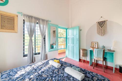 a bedroom with a bed and a desk and windows at Independent Villa with private pool in Siolim Goa in Oxel