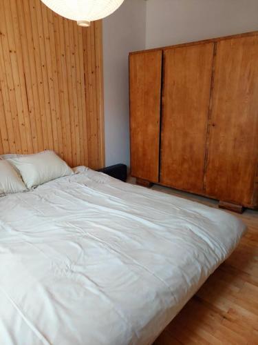 a bedroom with a large white bed with a wooden headboard at Postolove - a family home in Dubiny