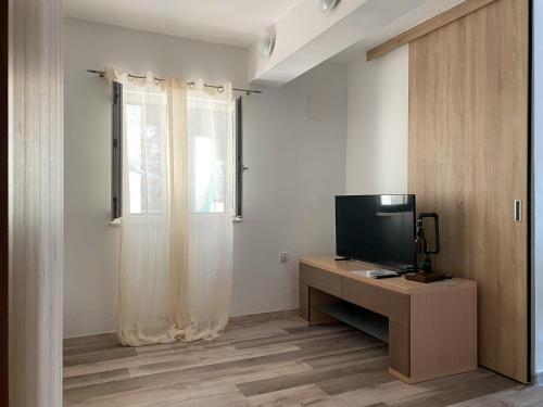 a room with a television on a desk with a window at Beach Apartments Luka in Tribanj-Krušćica