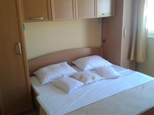 Una cama blanca con tres almohadas encima. en Apartments Lalic, en Vodice