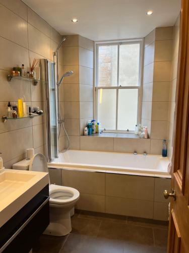 a bathroom with a tub and a toilet and a window at Quiet room in vibrant Bruntsfield with private parking in Edinburgh