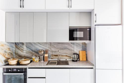 une cuisine blanche avec un évier et un micro-ondes dans l'établissement Silk Road Skyline Tashkent City, à Tachkent