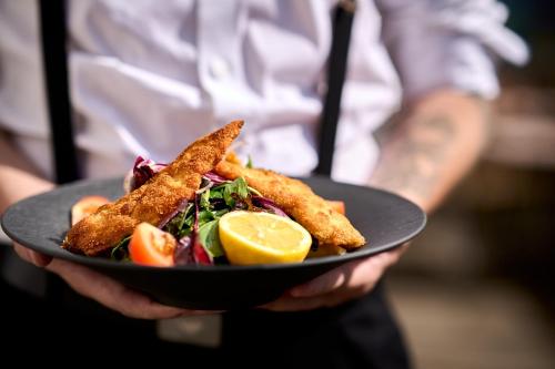 a person holding a plate of food with fish and salad at Hotel Tradizio in Mittelberg