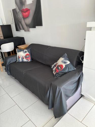 - un canapé noir dans le salon avec des oreillers dans l'établissement Naturiste Cap d'Agde Héliopolis F 4, au Cap d'Agde
