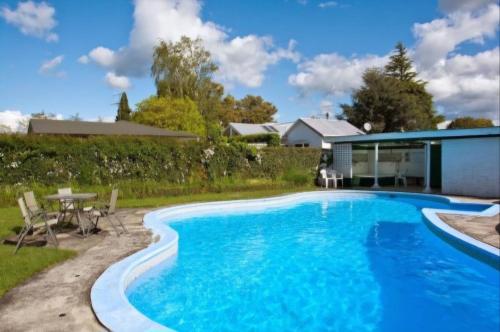 a swimming pool in a yard with a table and chairs at Garden Court Motel & Backpackers in Tauranga