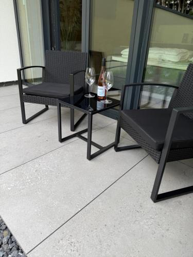 two chairs and a table with wine glasses on a patio at MIWO Friedrichshafen in FDH