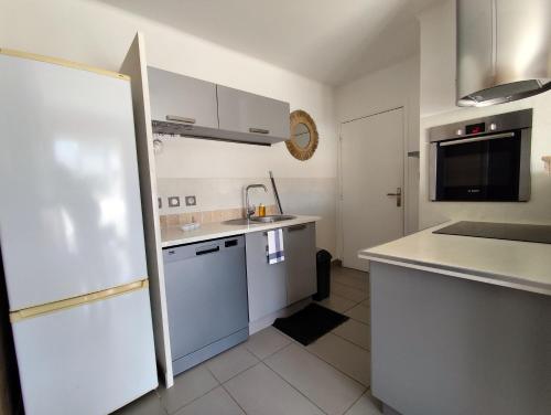 une cuisine avec des armoires blanches, un évier et un réfrigérateur dans l'établissement Giens, à Hyères