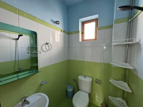 a green and white bathroom with a toilet and a sink at Villa Fjori Ksamil in Ksamil