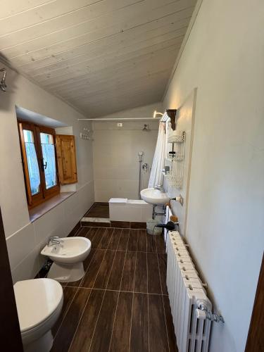 a bathroom with two toilets and a sink and a tub at Mancino in Poggibonsi