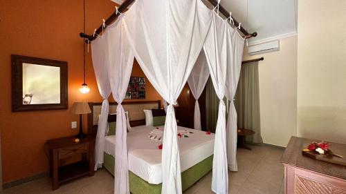 a bedroom with a canopy bed with white curtains at Palumbo Mnemba View Resort 