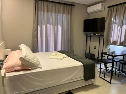 a bedroom with a bed and a table and a television at APARTAMENTOS BORA BORA II vila nova 600 METROS DA EXPOVILLE in Joinville