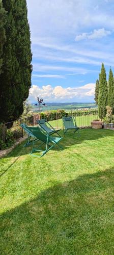 two green picnic tables in a yard with a fence at PassionToscane in San Giovanni dʼAsso