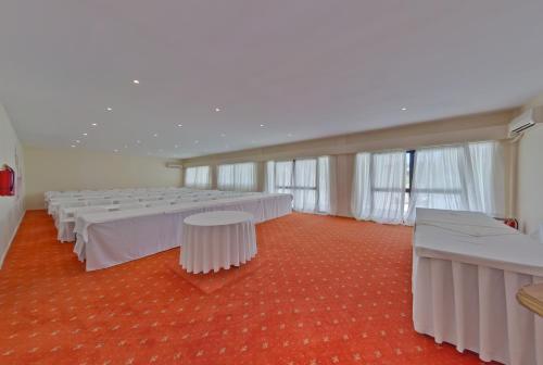 a room with rows of tables and white chairs at Palmariva Beach Hotel in Eretria
