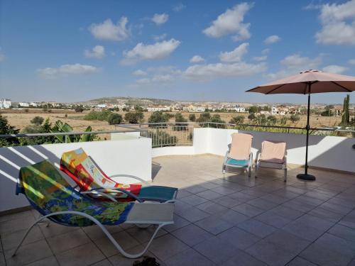 a patio with two chairs and an umbrella at Oceania Bay Village in Pyla
