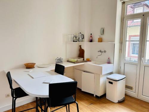 - une cuisine blanche avec une table et un évier dans l'établissement appartement spacieux en centre ville, à Strasbourg