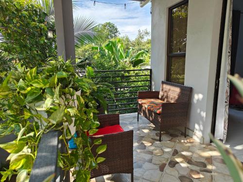 a porch with two chairs and plants on it at AJ House & Suites in Uvita