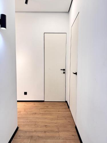 an empty corridor with white doors and a wooden floor at Atlantis resort, Issyk-kul in Chon-Sary-Oy