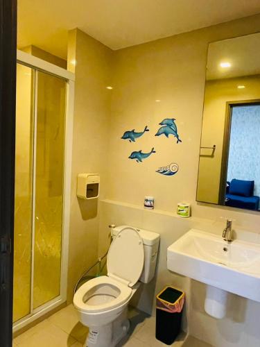 a bathroom with a toilet and a sink with dolphins on the wall at The base Central Pattaya 271 by Numam in Pattaya