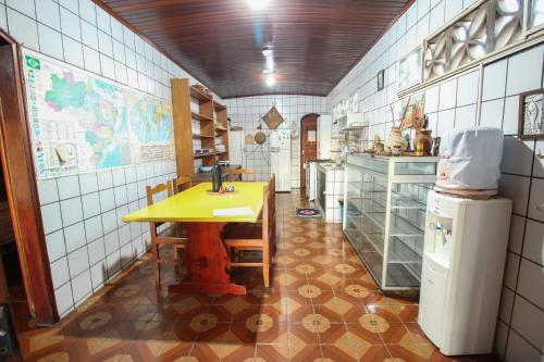 a kitchen with a yellow table in the middle at Hostel Roraima in Boa Vista
