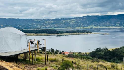 a large white tent on a hill next to a lake at Glamping Wayra in Guatavita