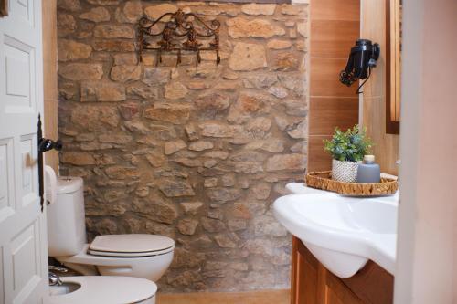 a bathroom with a stone wall and a toilet and sink at Casa del Castell de Toloriu in Toloríu