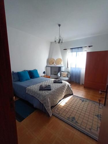 a bedroom with a bed with blue pillows on it at Casa marreiros in Aljezur