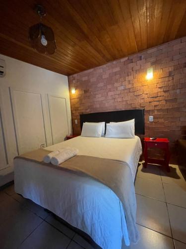 a bedroom with a large bed with a brick wall at Pousada Ilha da Magia in Florianópolis