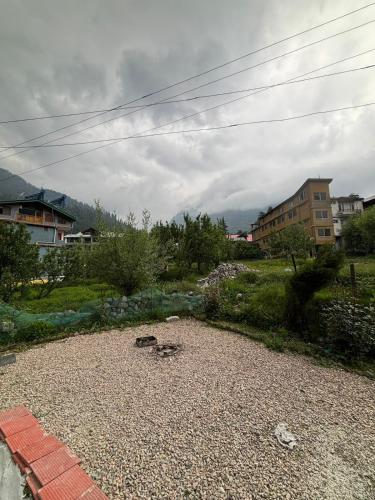 a view of a field with buildings in the background at Asha Cottage in Manāli