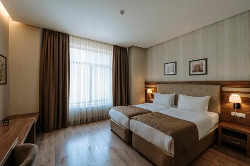 Una habitación de hotel con una cama y una ventana grande. en City Park Inn Baku, en Baku