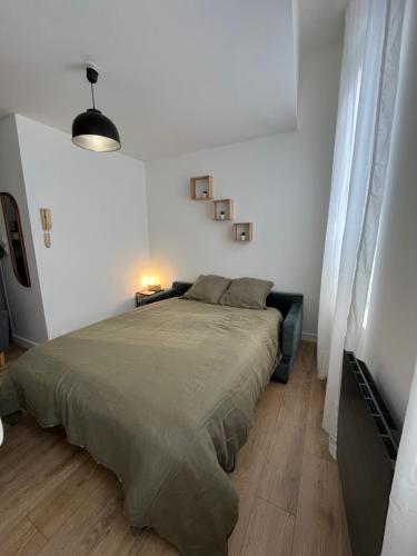 une chambre avec un grand lit dans une pièce blanche dans l'établissement Les horizons de Jules, à Amiens