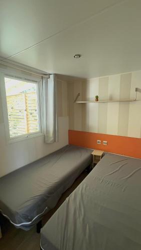 une petite chambre avec deux lits et une fenêtre dans l'établissement Mobil-home Le Manosely confort 6 pers Climatisé, à Agde