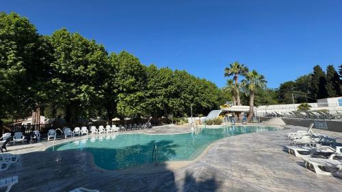 une piscine avec des chaises blanches et des arbres et des arbres dans l'établissement Mobil-home Le Manosely confort 6 pers Climatisé, à Agde