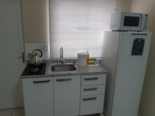a kitchen with a refrigerator and a sink and a microwave at Apto JK Universitário - Express in Santa Cruz do Sul