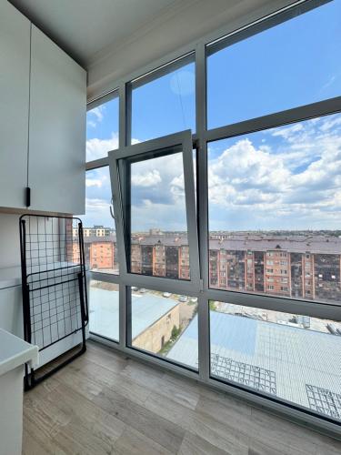 a room with large windows with a view of a city at A-Six Apartment ЖК Family park in Karagandy