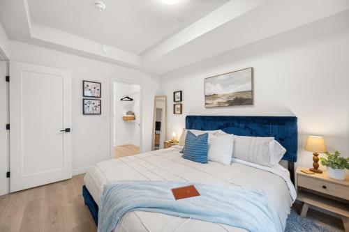 a white bedroom with a blue and white bed at Chic Condo with Stylish Amenities in White Rock in Surrey