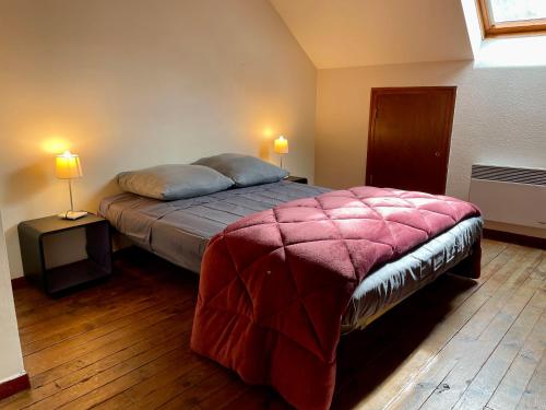 - une chambre avec un lit avec une couverture rouge et 2 lampes dans l'établissement Conques en Rouergue, maison de village,Grand Vabre, à Conques-en-Rouergue