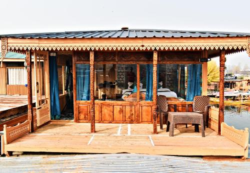 a house with a wooden deck with a table and chairs at Honolulu Group Of Houseboats in Srinagar