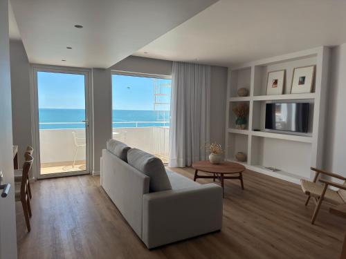 a living room with a couch and a view of the ocean at Apartamentos Rossio Mar in Albufeira