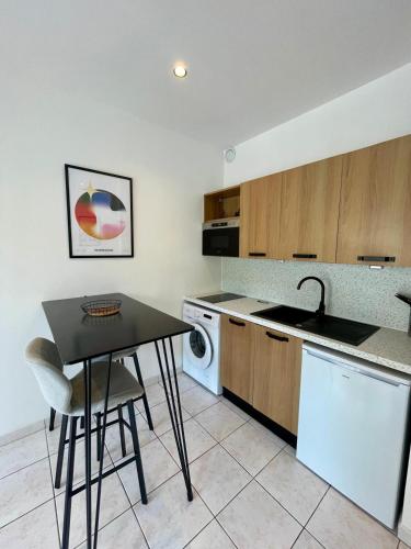 La cuisine est équipée d'une table, d'un évier et d'un lave-vaisselle. dans l'établissement Joli appartement au bord de mer, à Nice