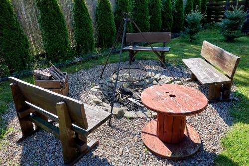 a garden with two benches and a table and a fire place at Aloha Glamp - okrągłe domki przy rzece - balia i sauna - Energylandia in Zagórnik