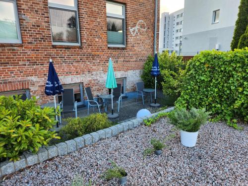 a garden with chairs and umbrellas in front of a building at Unterwegs ins Apartmenthaus ehemalige Apartmenthaus Unterwegs in Rostock