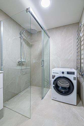 a washing machine in a bathroom with a shower at River View Apartment in Kaunas