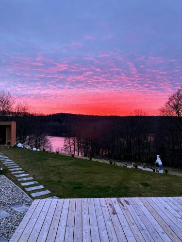 a wooden deck with a sunset in the background at Stodoła Rzym - domek, jacuzzi, sauna, jezioro, las in Kożyczkowo