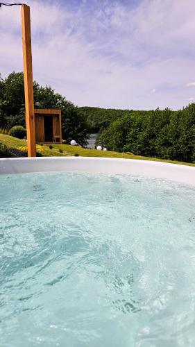 a large pool of blue water in front of a house at Stodoła Rzym - domek, jacuzzi, sauna, jezioro, las in Kożyczkowo