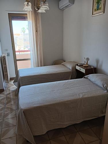 two beds in a hotel room with a window at Casa Luciana in Maglie